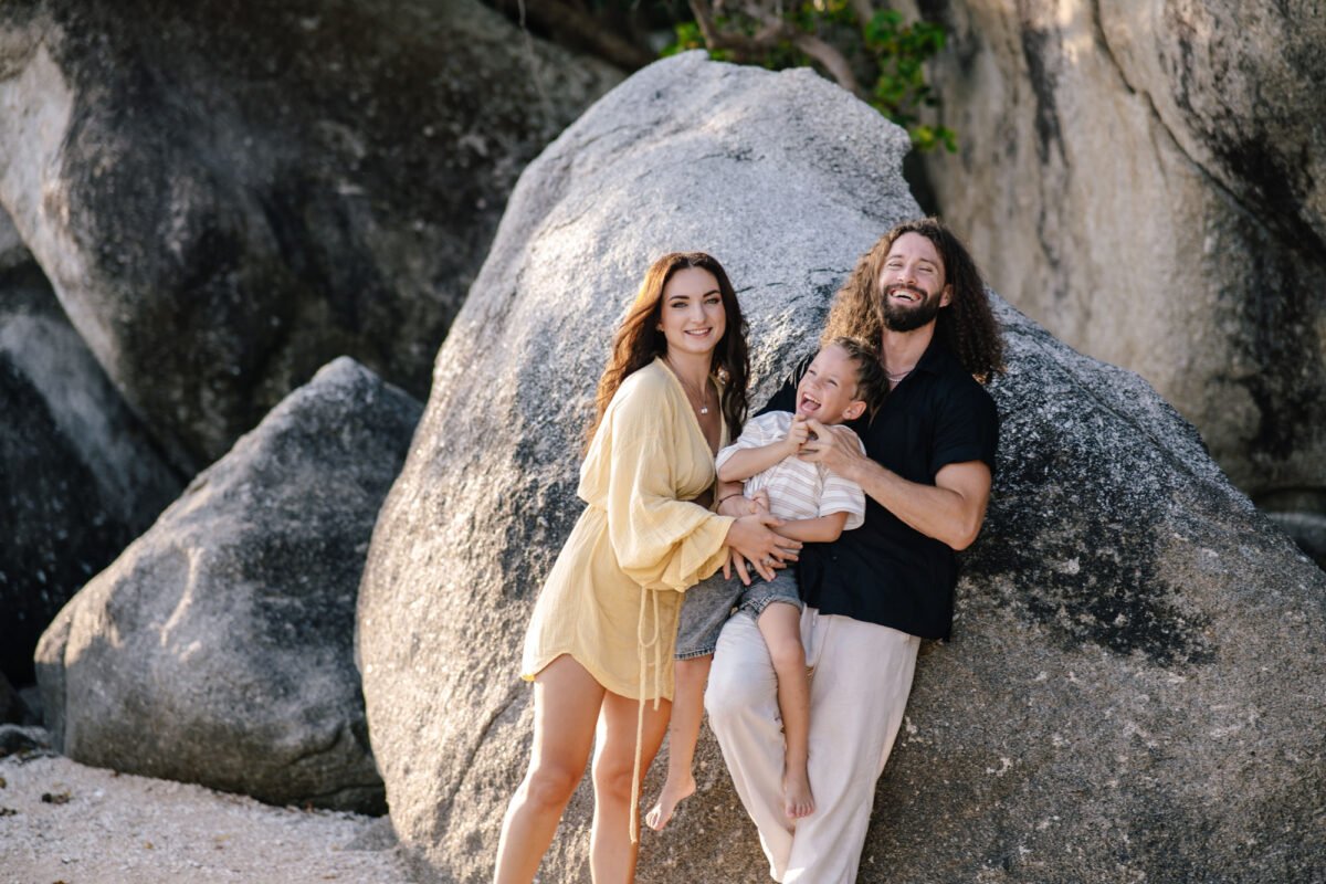 Couple with newborn on the rocks at the beach, Koh Samui family story